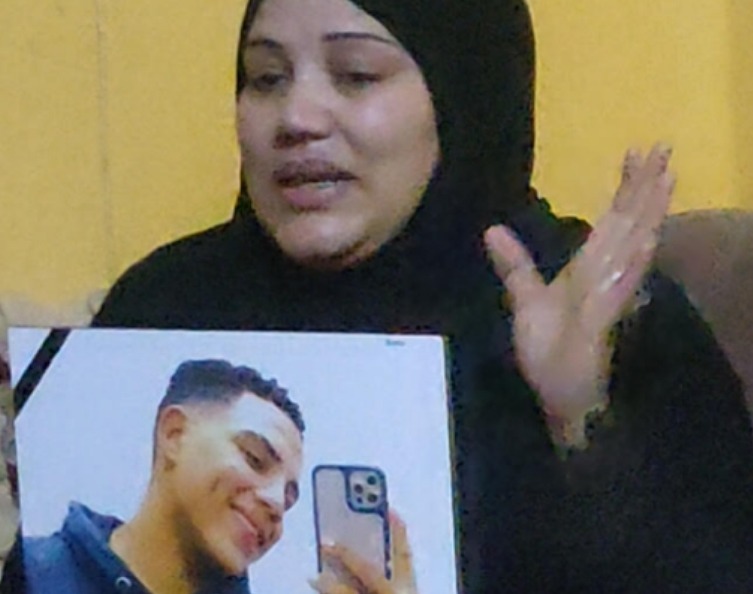 والدة المجني عليه تحمل صورته