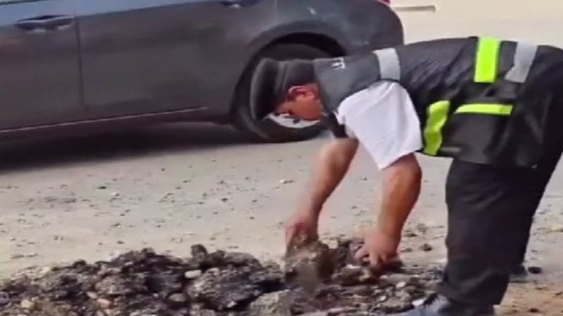 مساعد شرطة يزيل حجارة من الطريق العام 